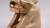 Antropomorficzna postać z głową tygrysa, okrutnym pyskiem. Rzeźba pokryta smokami