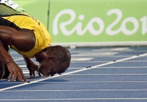 Usain Bolt całuje bieżnię, po kolejnej wygranej, fot. PAP/EPA/YOAN VALAT