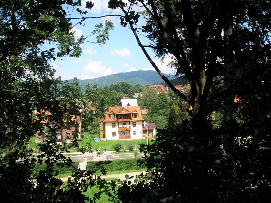 Spojrzenie na dolinę przez okno gęstej zieleni z południowego grzbietu, na którym zlokalizowany jest park i właściwy zdrój.
