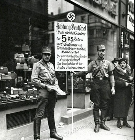The sign reads: “Germans, Attention! This shop is owned by Jews. Jews damage the German economy and pay their German employees starvation wages. The main owner is the Jew Nathan Schmidt.” (1st April, 1933)