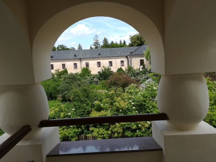 Widok z wejścia do sali teatralnej: ogród i  barokowy klasztor dominikański