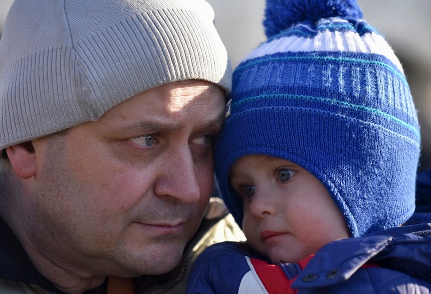 Ojciec z synem w ostrzeliwanym przez Rosjan mieście nieopodal Kijowa, stolicy Ukrainy. Fot. PAP/EPA/OLEG PETRASYUK