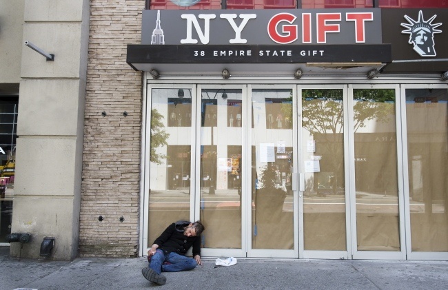 Bezdomny mężczyzna leży przed zamkniętym sklepem w Nowym Jorku. Zamrożenie gospodarki wywołało falę bezrobocia, fot. PAP/EPA/JUSTIN LANE