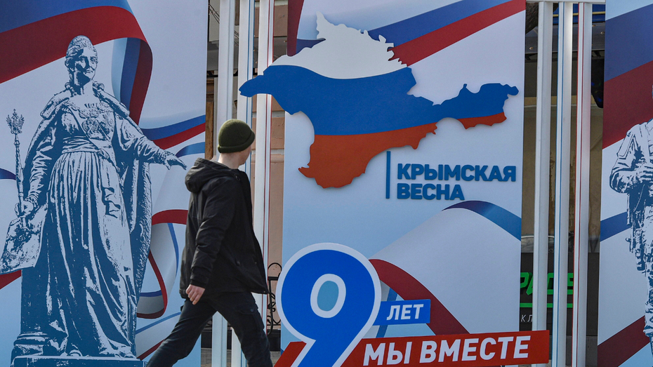 Mężczyzna przechodzący obok baneru z okazji 9 rocznicy aneksji Krymu przez Rosję / źródło: PAP/EPA/STRINGER