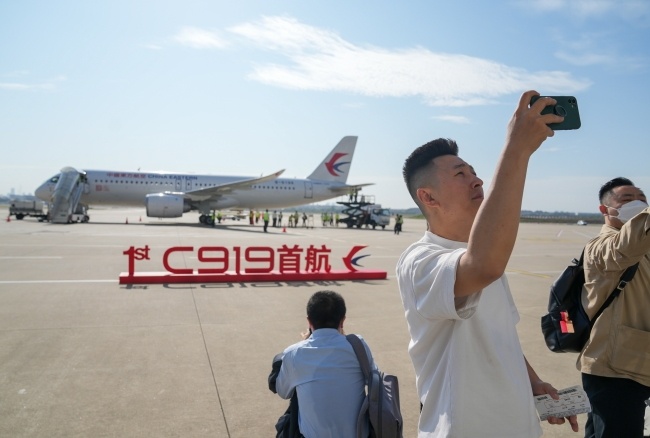 Pasażerowie robią sobie zdjęcia na tle chińskiego samolotu C919, fot. PA/XINHUA / Ding Ting CHINA OUT