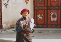 Kobieta tybetańska z młynkiem do modlitwy idzie sobie ulicą