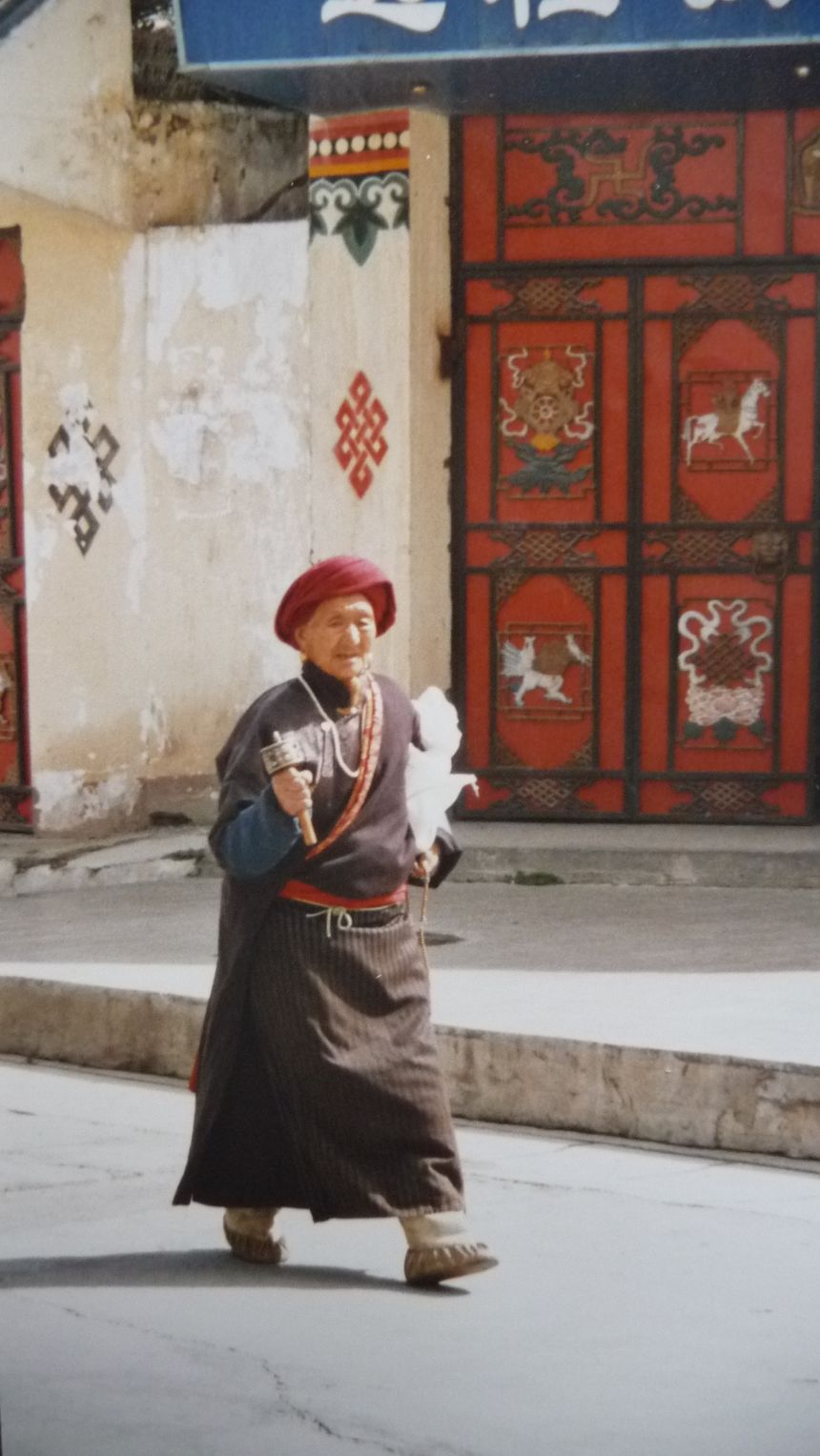 Kobieta tybetańska z młynkiem do modlitwy idzie sobie ulicą