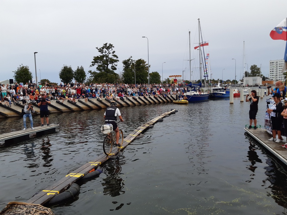 Zawody w jeździe po desce na wodzie wymagają zmysłu równowagi. Kołobrzeg 2019. Port Jachtowy.