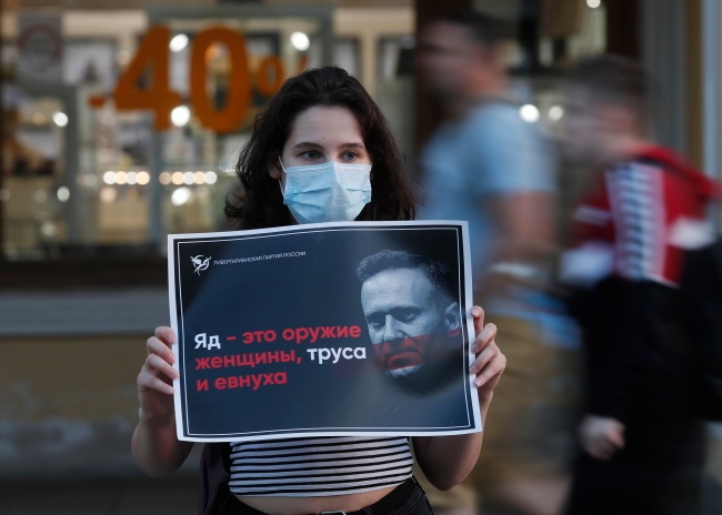 Rosjanka protestująca przeciw otruciu Nawalnego trzyma plakat z napisem: "Trucizna jest bronią kobiety, tchórza i eunucha". Fot. PAP/EPA/ANATOLY MALTSEV