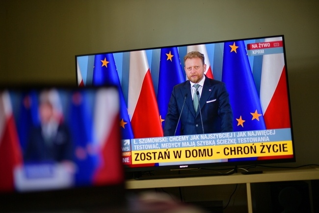 Minister zdrowia Łukasz Szumowski (na ekranie telewizora) podczas konferencji prasowej, fot. PAP/Marcin Obara