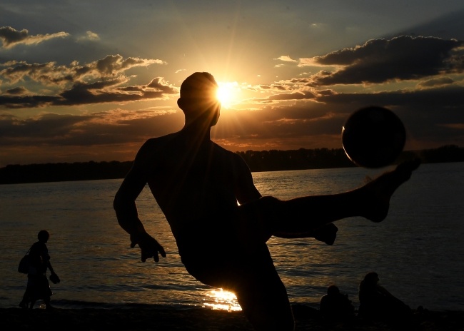 Mężczyzna gra w piłkę nad Wołgą w Samarze. Fot. PAP/EPA/Facundo Arrizabalaga