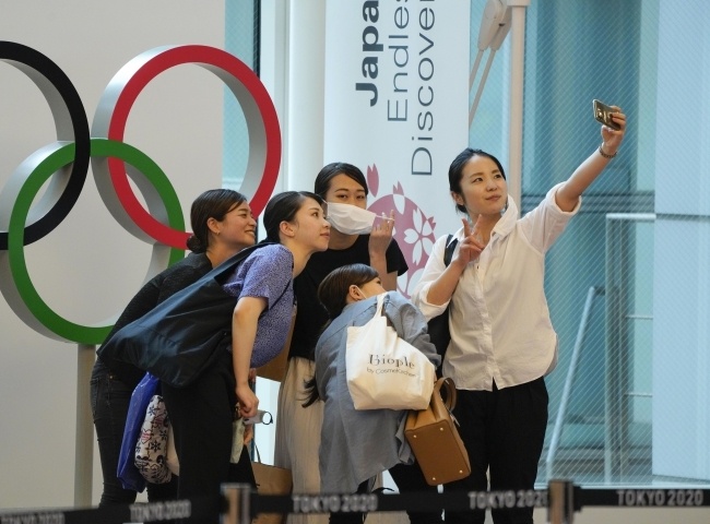 Turyści robią sobie selfie przed symbolem Igrzysk Olimpijskich ustawionym w terminalu przylotów Międzynarodowego Lotniska Tokio w Haneda, fot. PAP/EPA/KIMIMASA MAYAMA