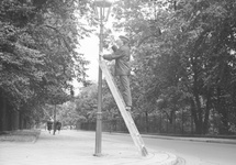Latarnik włączający latarnię gazową przy ul. Agrykola w Warszawie, zdj. wykonano 1967-1979. Lampy gazowe działają tam do dziś. Fot. NAC (Narodowe Archiwum Cyfrowe)