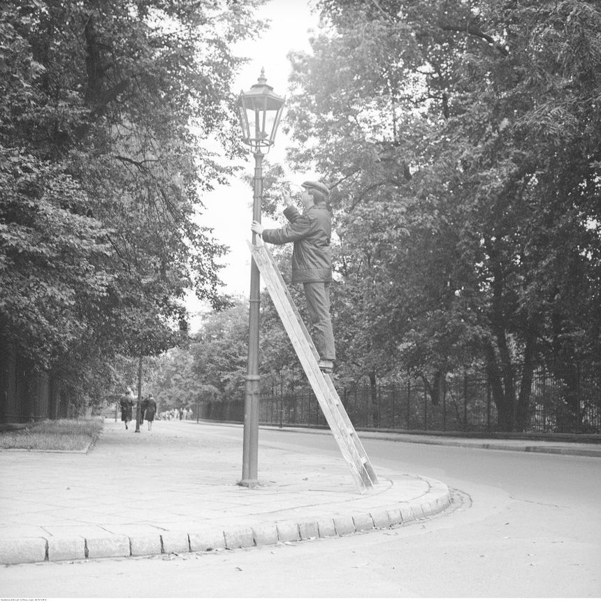 Latarnik włączający latarnię gazową przy ul. Agrykola w Warszawie, zdj. wykonano 1967-1979. Lampy gazowe działają tam do dziś. Fot. NAC (Narodowe Archiwum Cyfrowe)